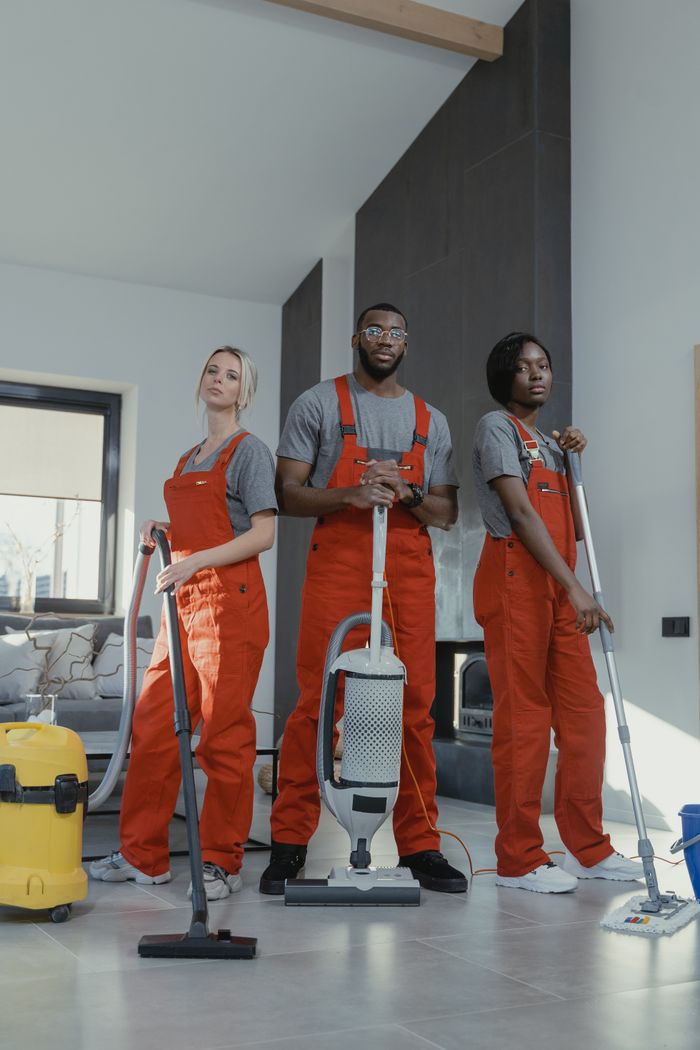 gallery-02 Three cleaners in uniform with equipment in a modern home interior, showcasing teamwork and professionalism.